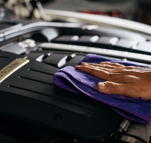 Close up on a men's hand cleaning the top of an engine with a cloth