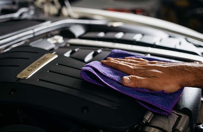 Close up on a men's hand cleaning the top of an engine with a cloth